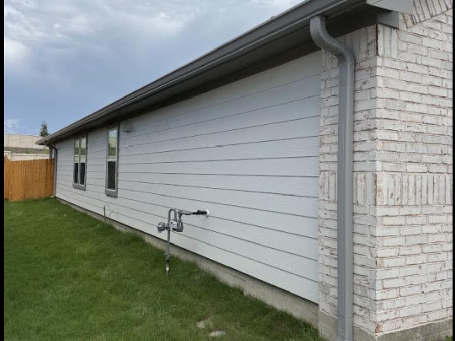 White home exterior with installed downspout and seamless gutter run.